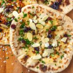 A Peshwari naan bread topped with raisins, almonds and coriander leaf.