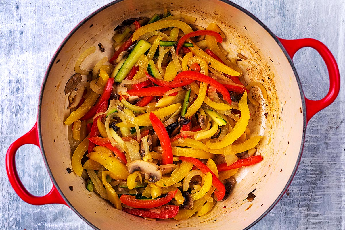 A large cooking pot with sliced vegetables cooking in it.