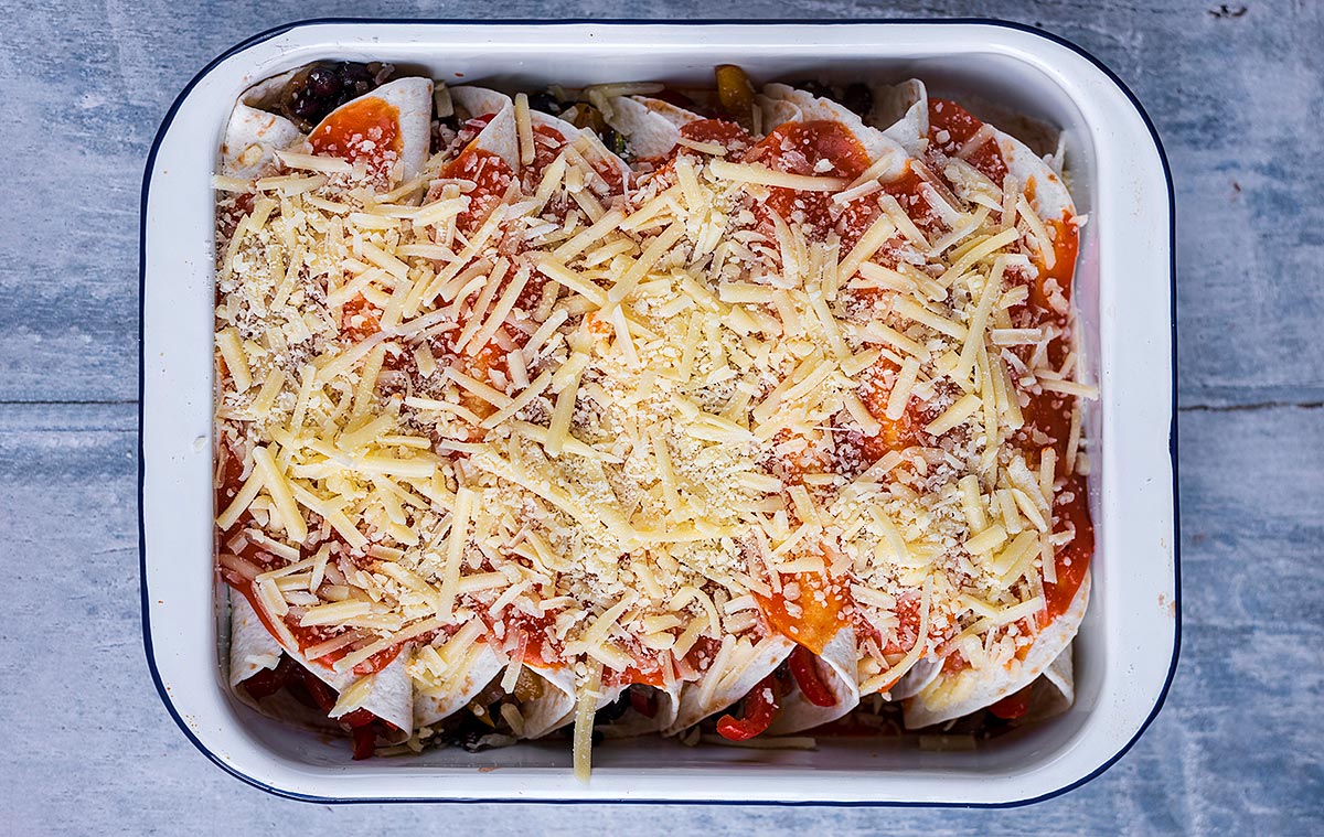 A dish of enchiladas covered in sauce and grated cheese.