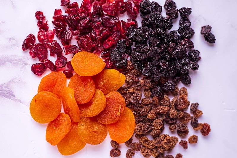 Dried apricots, cranberries, raisins and sultanas on a marble surface.