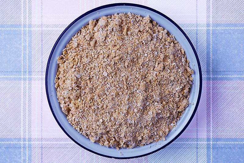 A baking dish with fruit completely covered in an oaty mixture