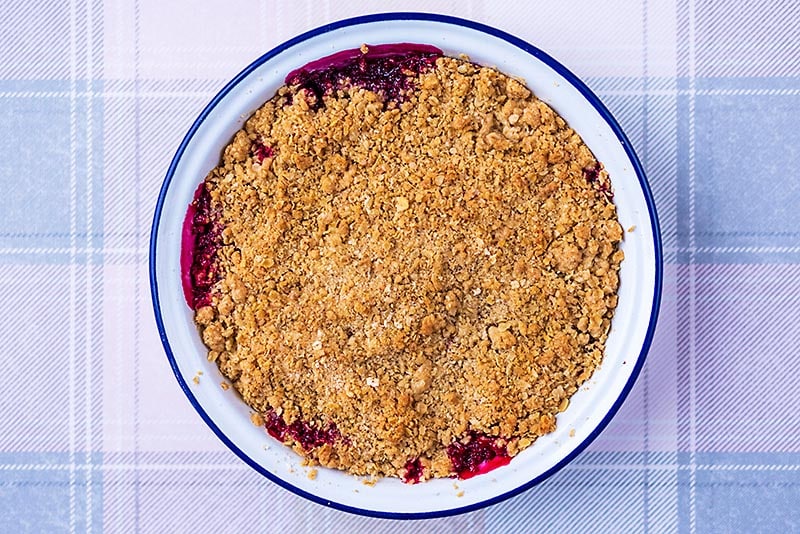 A mixed berry crisp fresh from the oven with a golden brown top and some fruit seeming around the edge