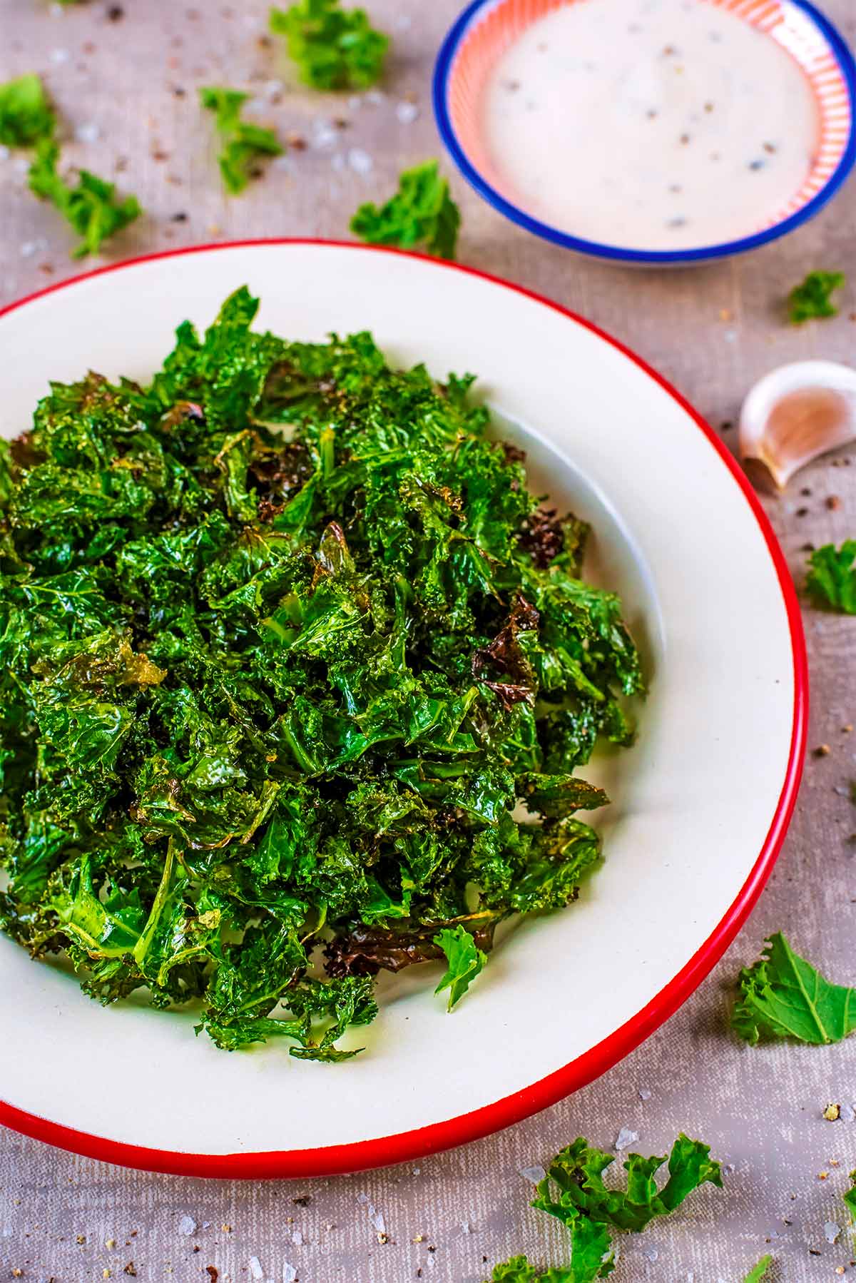 Roasted kale on a plate with a small dish of ranch dip in the background.