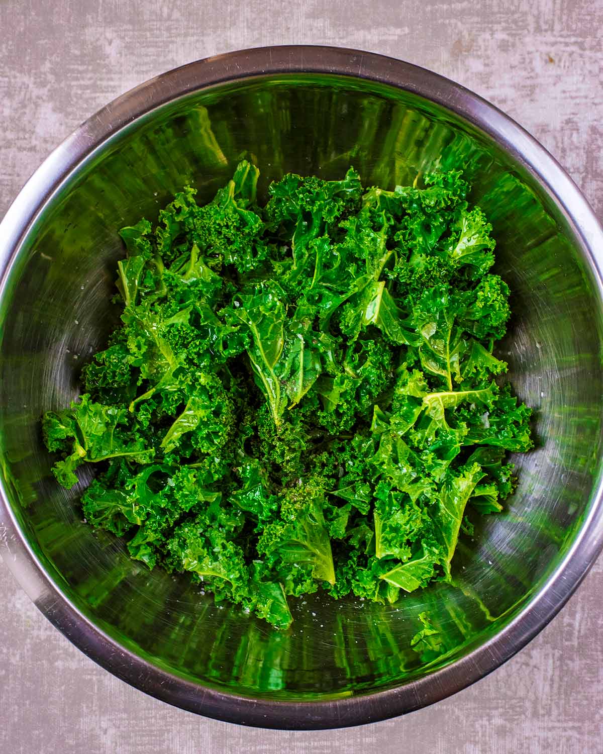 A mixing bowl containing curly kale.