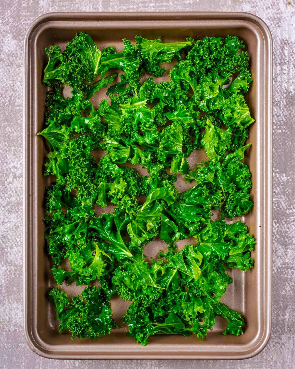 Oil coated kale on a baking tray.