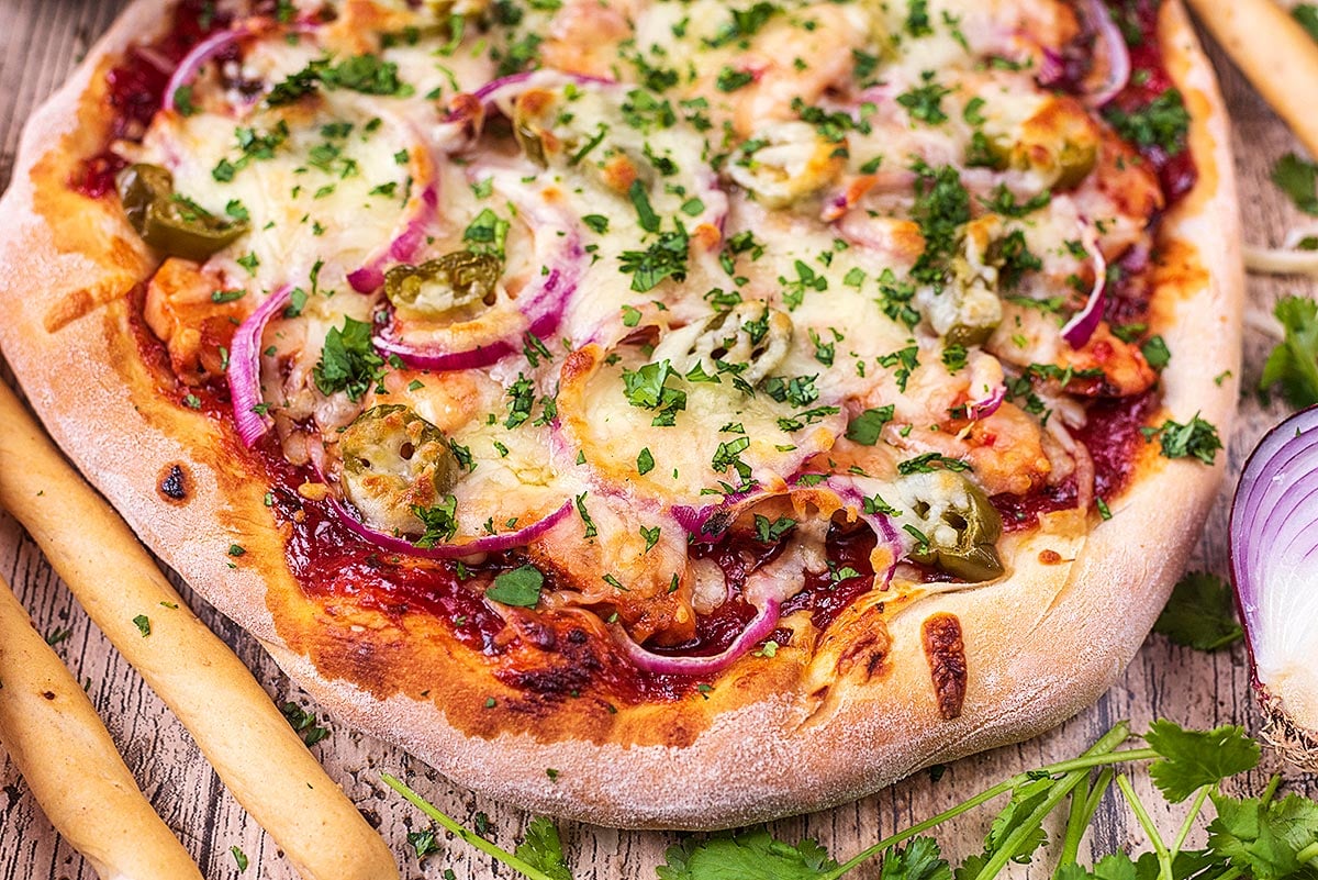 BBQ chicken pizza on a wooden surface.