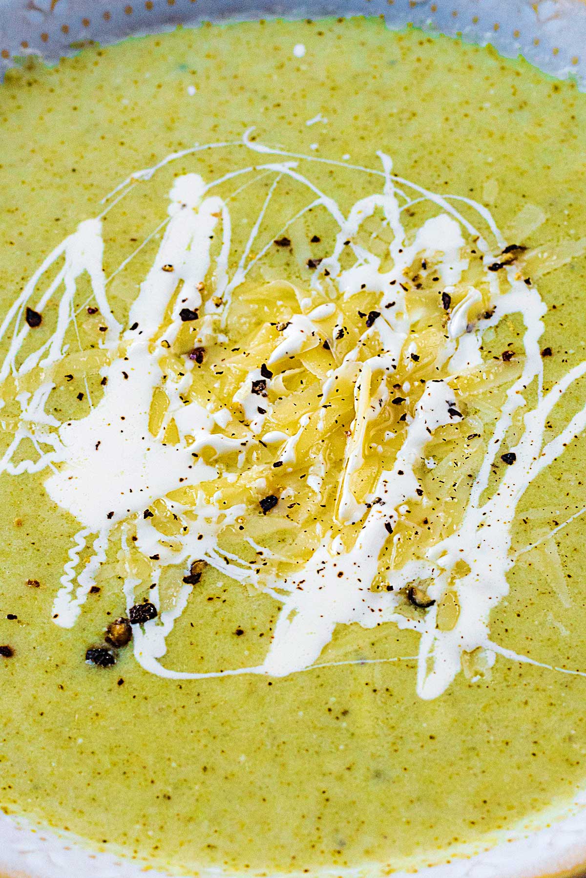 Grated cheese and cream on the surface of some soup.