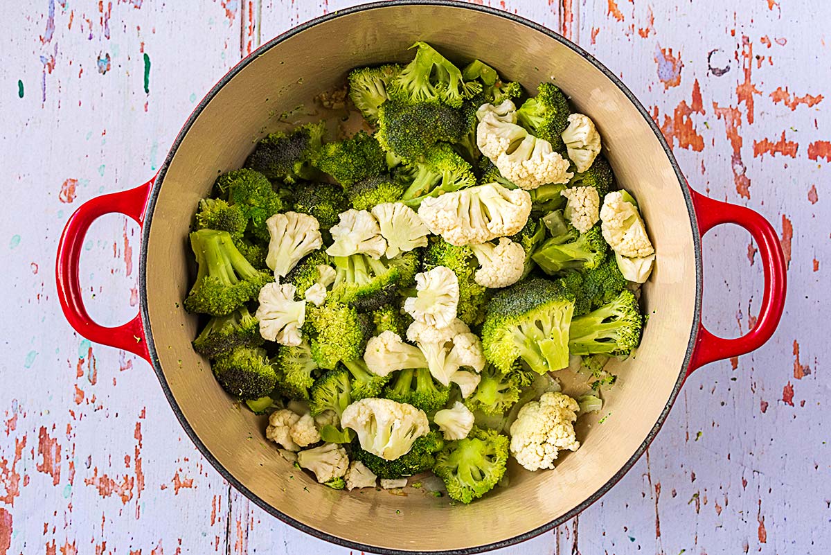 Broccoli and cauliflower florets cooking in a large pan.
