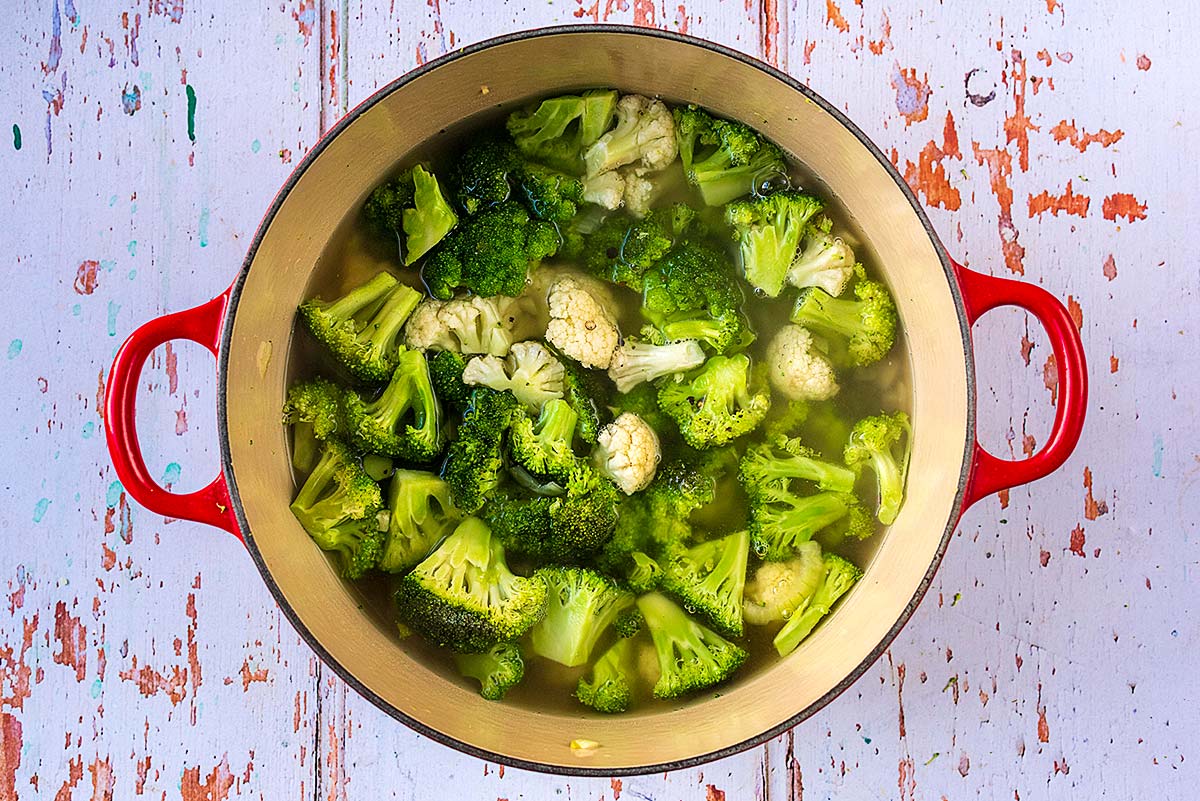 Florets of broccoli and cauliflower in stock in a large pan.