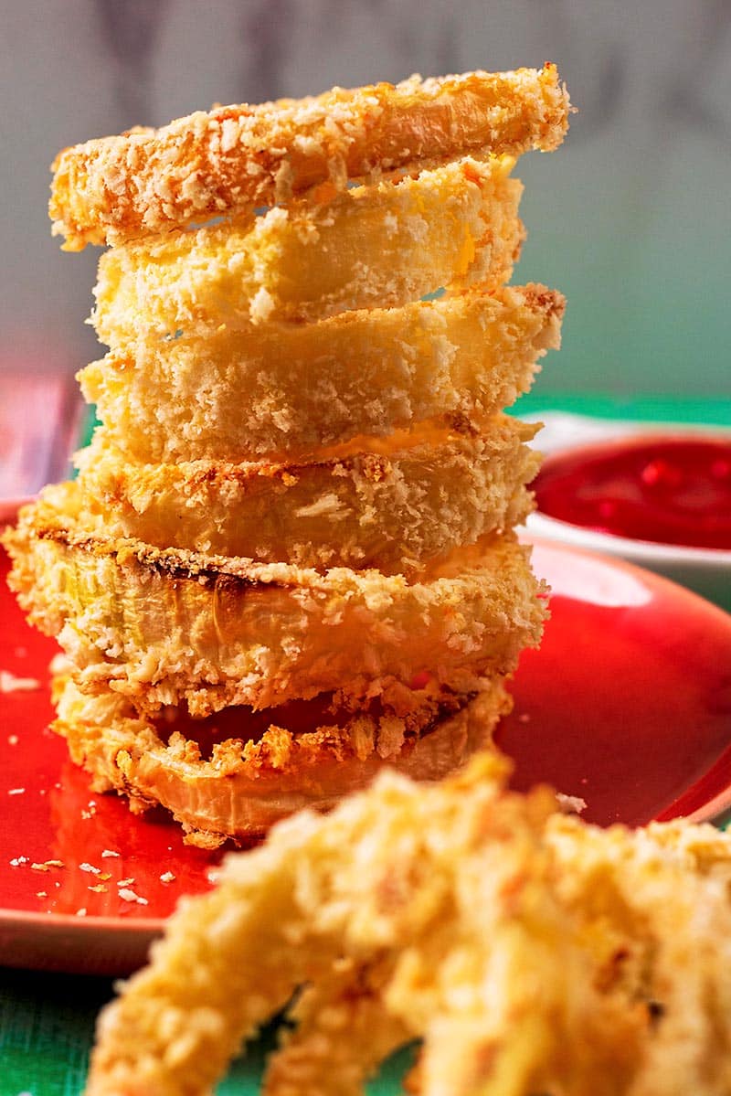 A stack of six onion rings on an orange plate.