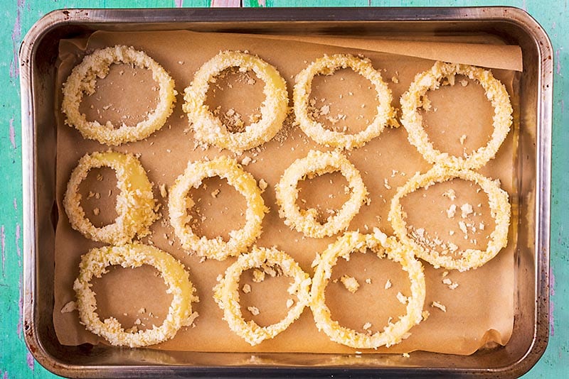 A lined baking tray covered in onion rings.