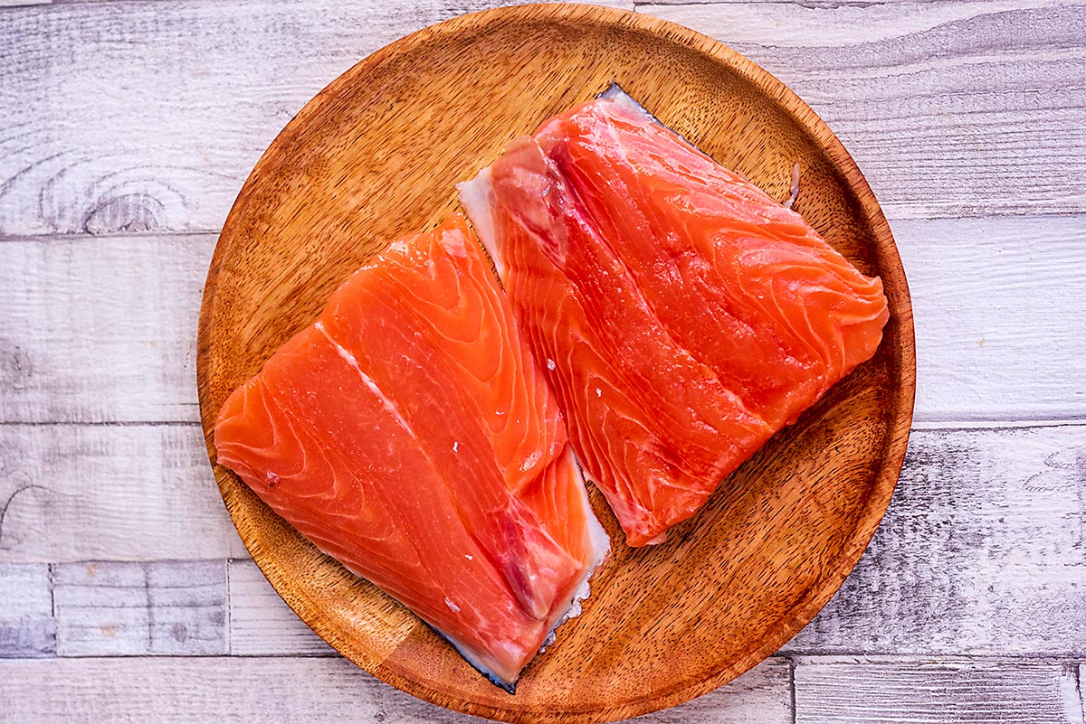 Two raw salmon fillets on a plate.