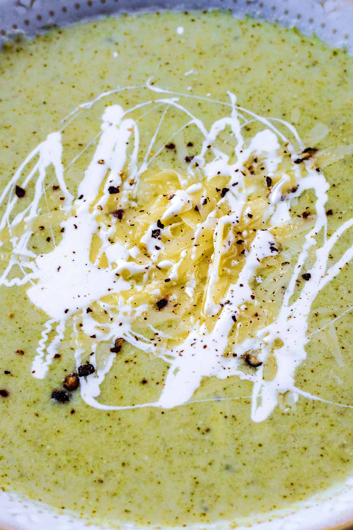 Grated cheese and cream on the surface of some soup.