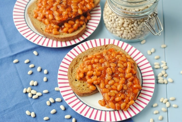 Two plates of beans on toast sat on a blue towel.