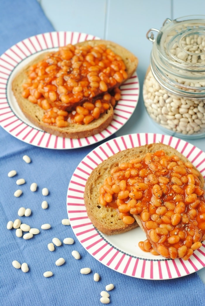 Two plates of beans on toast next to a jar of uncooked beans.