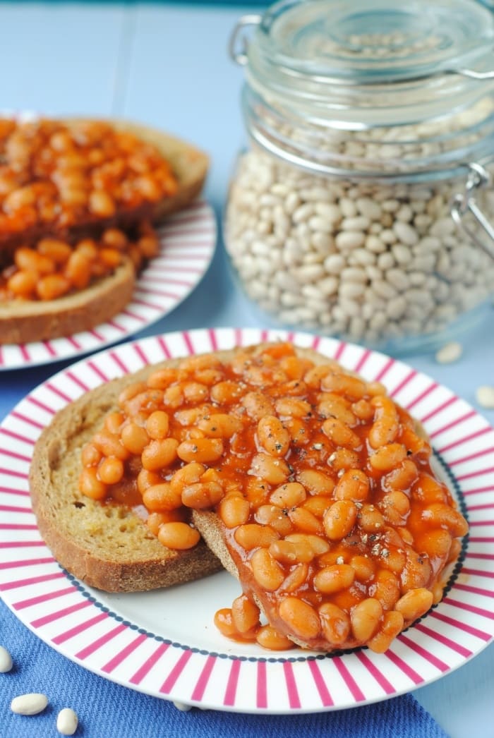 A plate of slow cooker baked beans in front of a jar of dried beans.