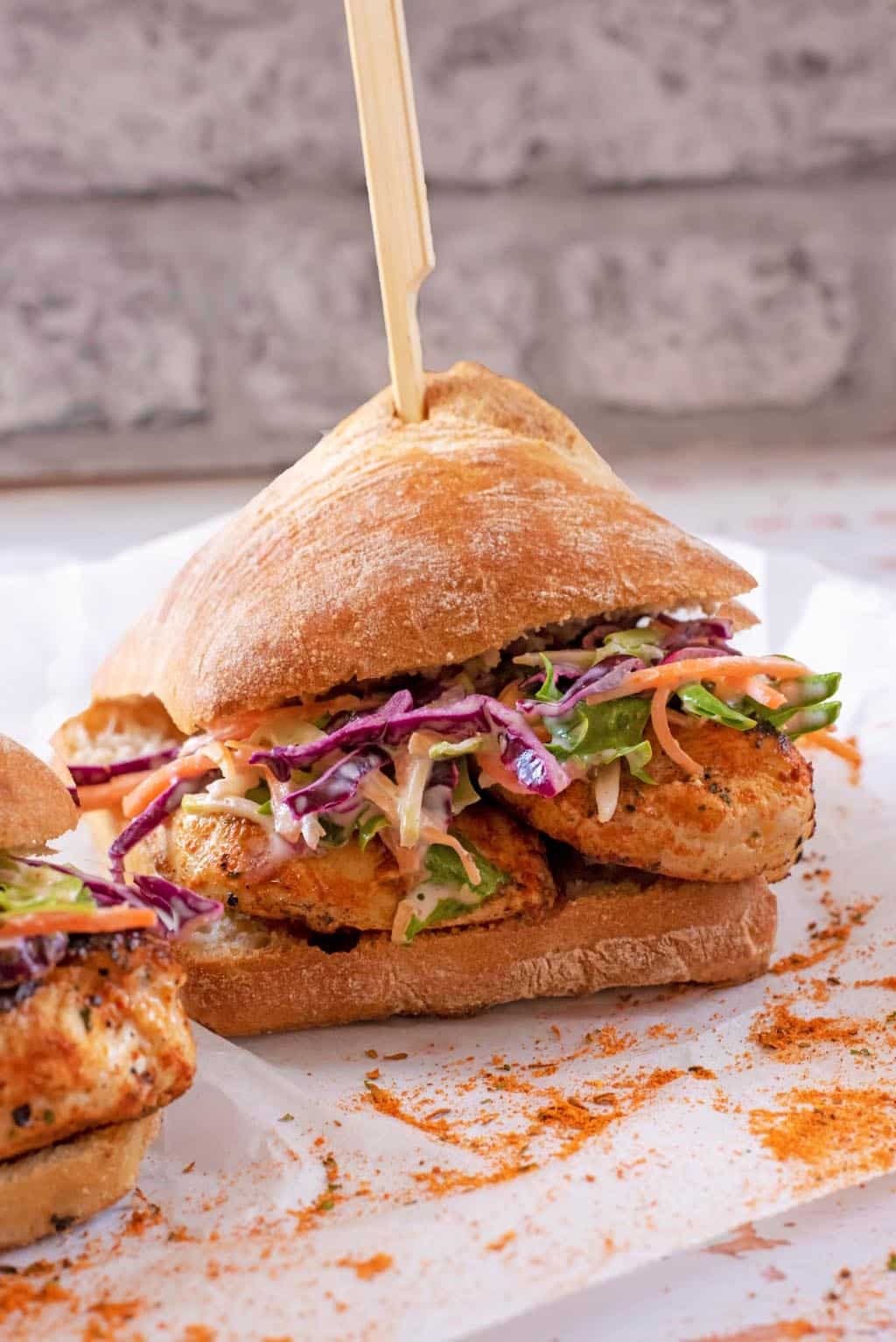 Chicken Burger and slaw in a bun with a wooden skewer through it all.