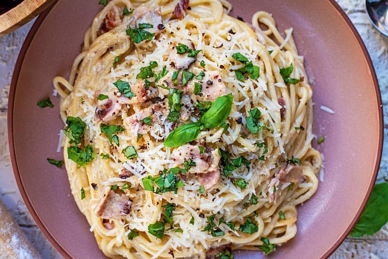 Spaghetti Carbonara on a plate with basil on top.