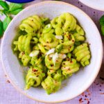 A bowl of Creamy Avocado Pasta with chilli flakes sprinkled on top.