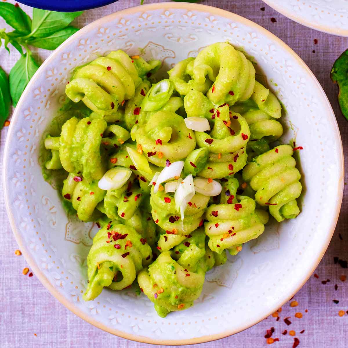 A bowl of Creamy Avocado Pasta with chilli flakes sprinkled on top.
