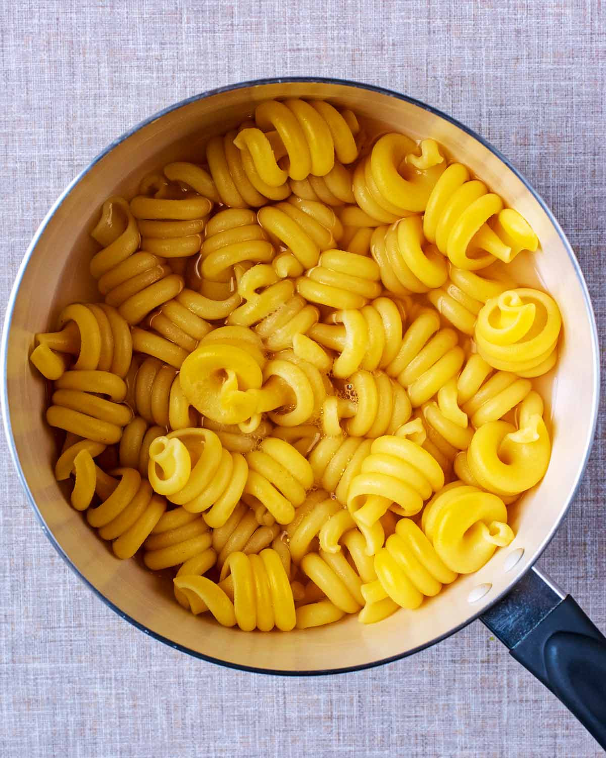 Pasta spirals cooking in a saucepan.