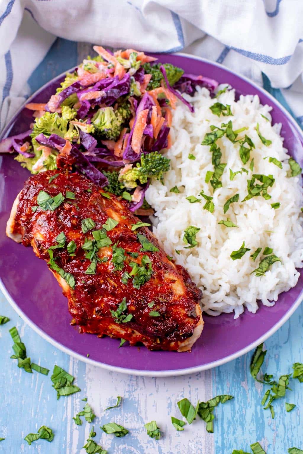 Coated chicken on a plate with rice and slaw.
