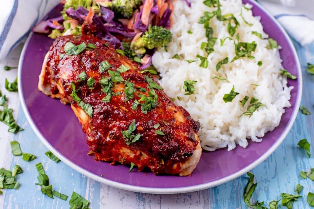 Marinated chicken. rice and slaw on a purple plate.