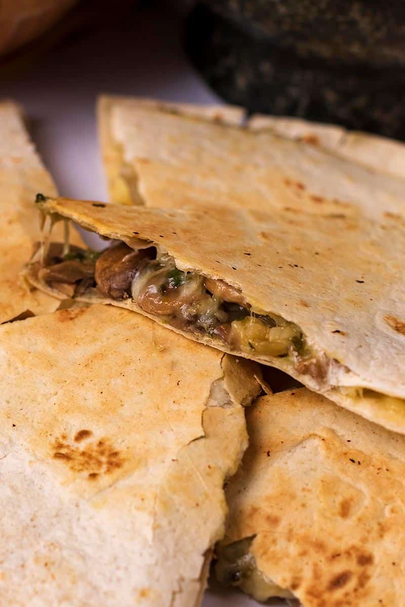 A stack of quesadilla slices with one showing the filling.