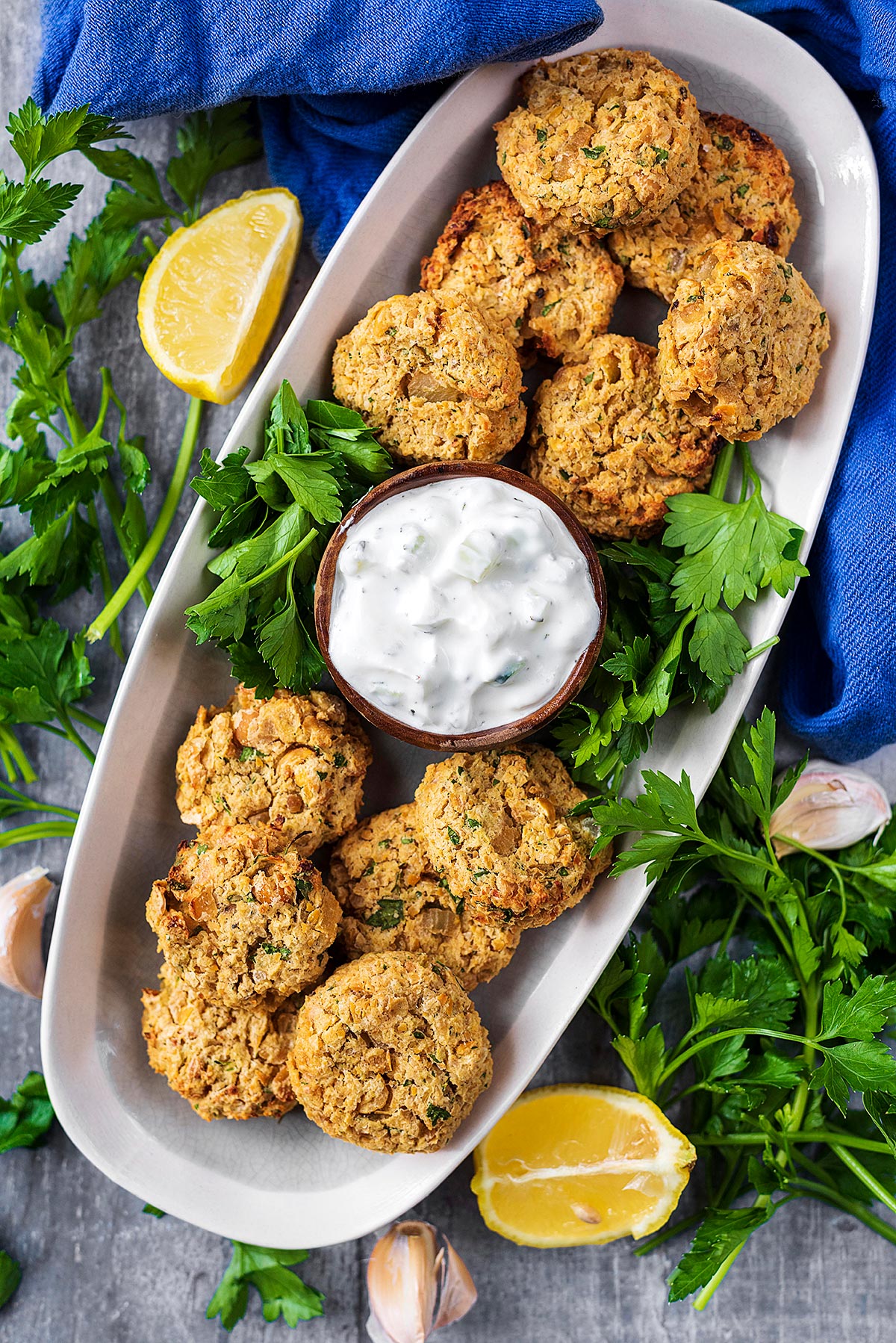 A long serving dish containing falafel and a small pot of white dip