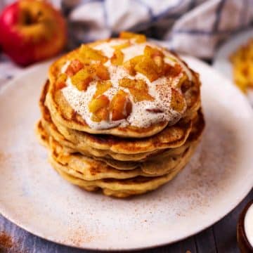 A stack of Apple and Cinnamon Pancakes next to some apples