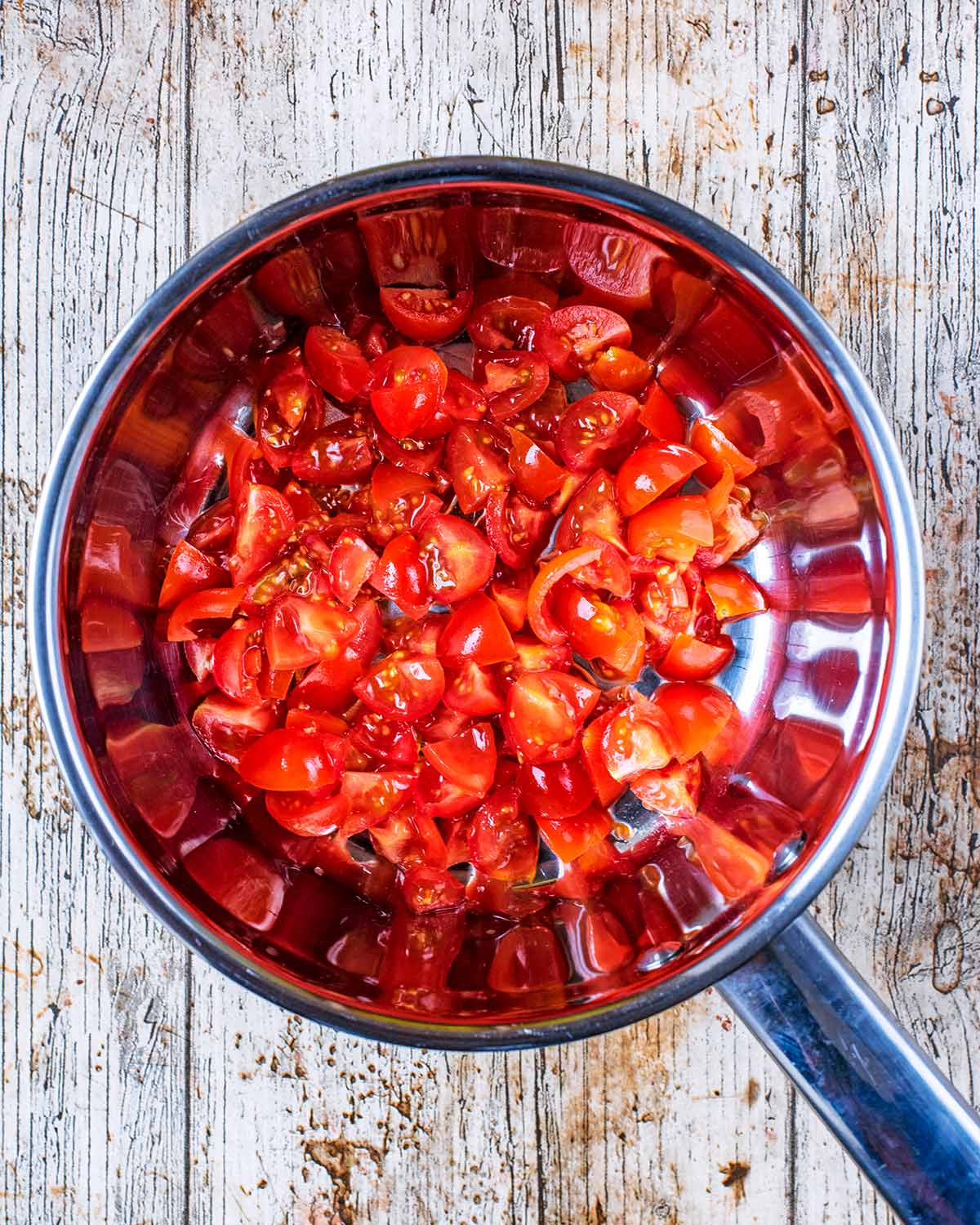 A saucepan containing chopped tomatoes.