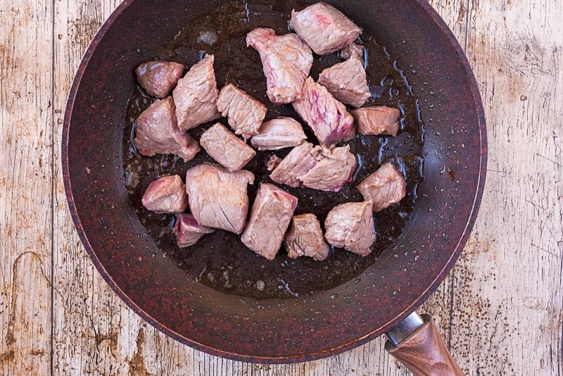 A frying pan containing browned chunks of beef.