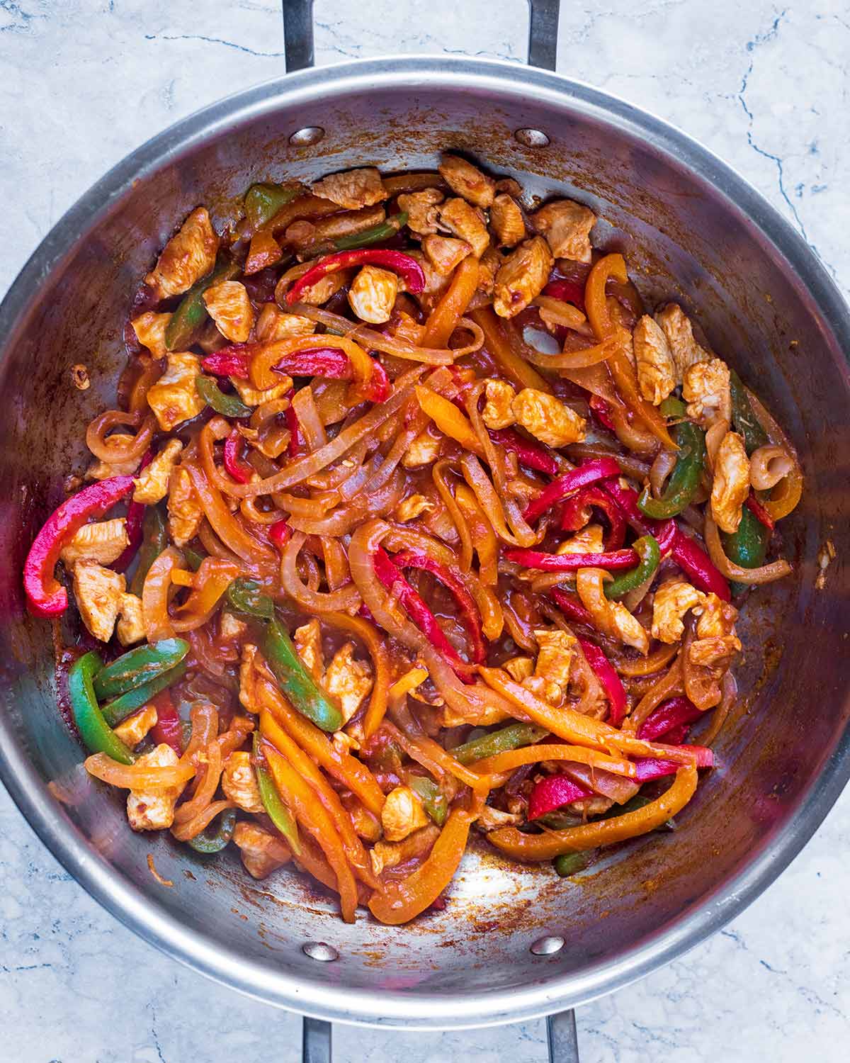 A large pan with chopped chicken and vegetables cooking in a sauce.