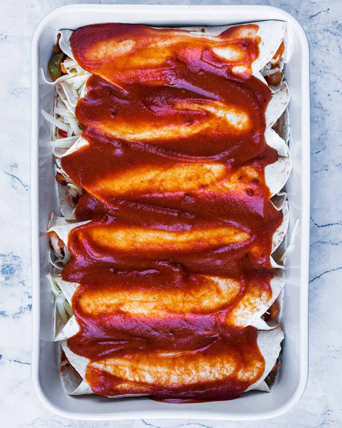 A baking dish with six enchiladas covered in sauce.