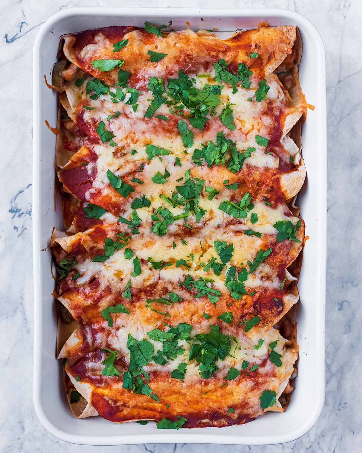 Baked enchiladas with chopped cilantro sprinkled on top.