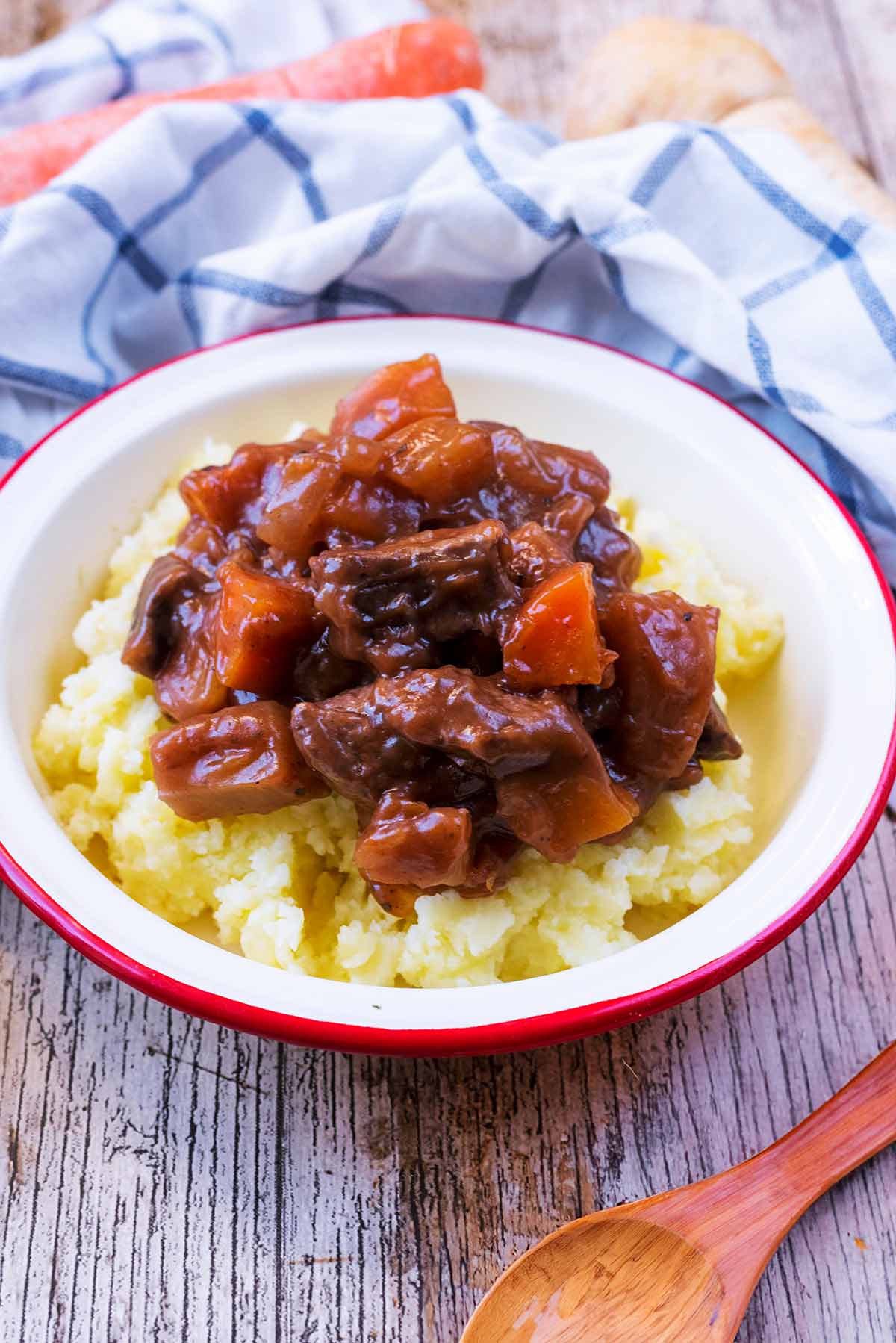 A white bowl containing mashed potato topped with beef casserole.