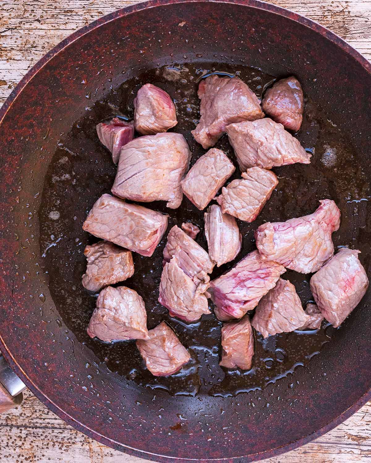 A frying pan containing browned chunks of beef.