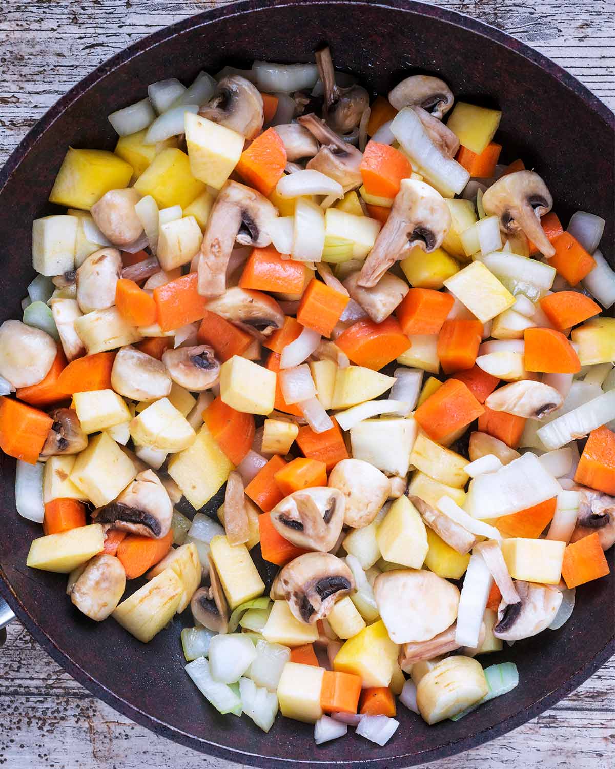 Chopped vegetables cooking in a frying pan.