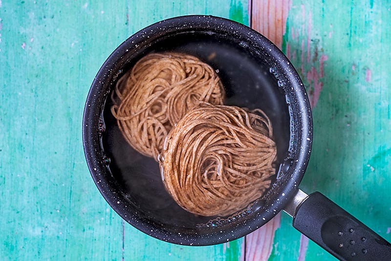 A saucepan containing two nests of wholewheat noodles.