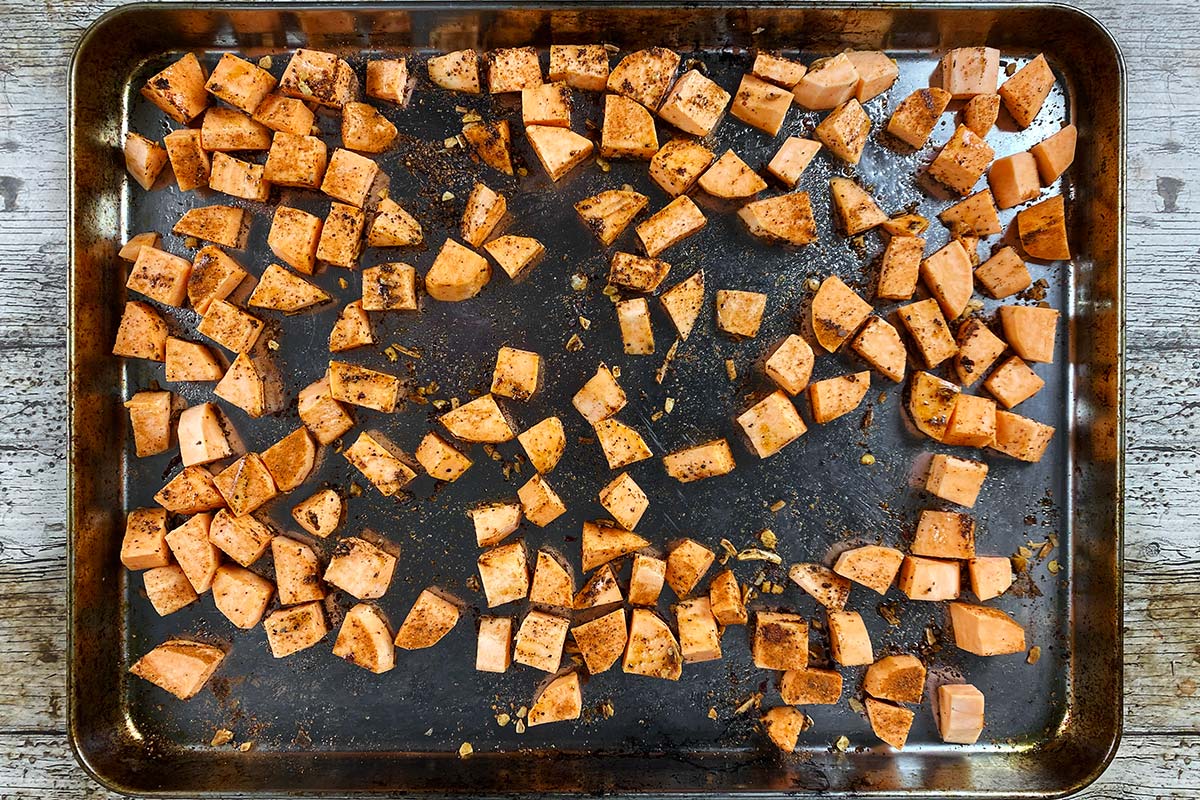 A baking tray with cubes of sweet potato spread over it.