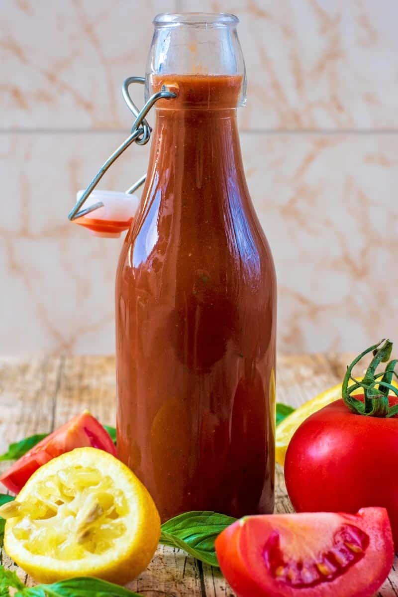 Tomato Vinaigrette in a glass bottle in front of a tiled background.