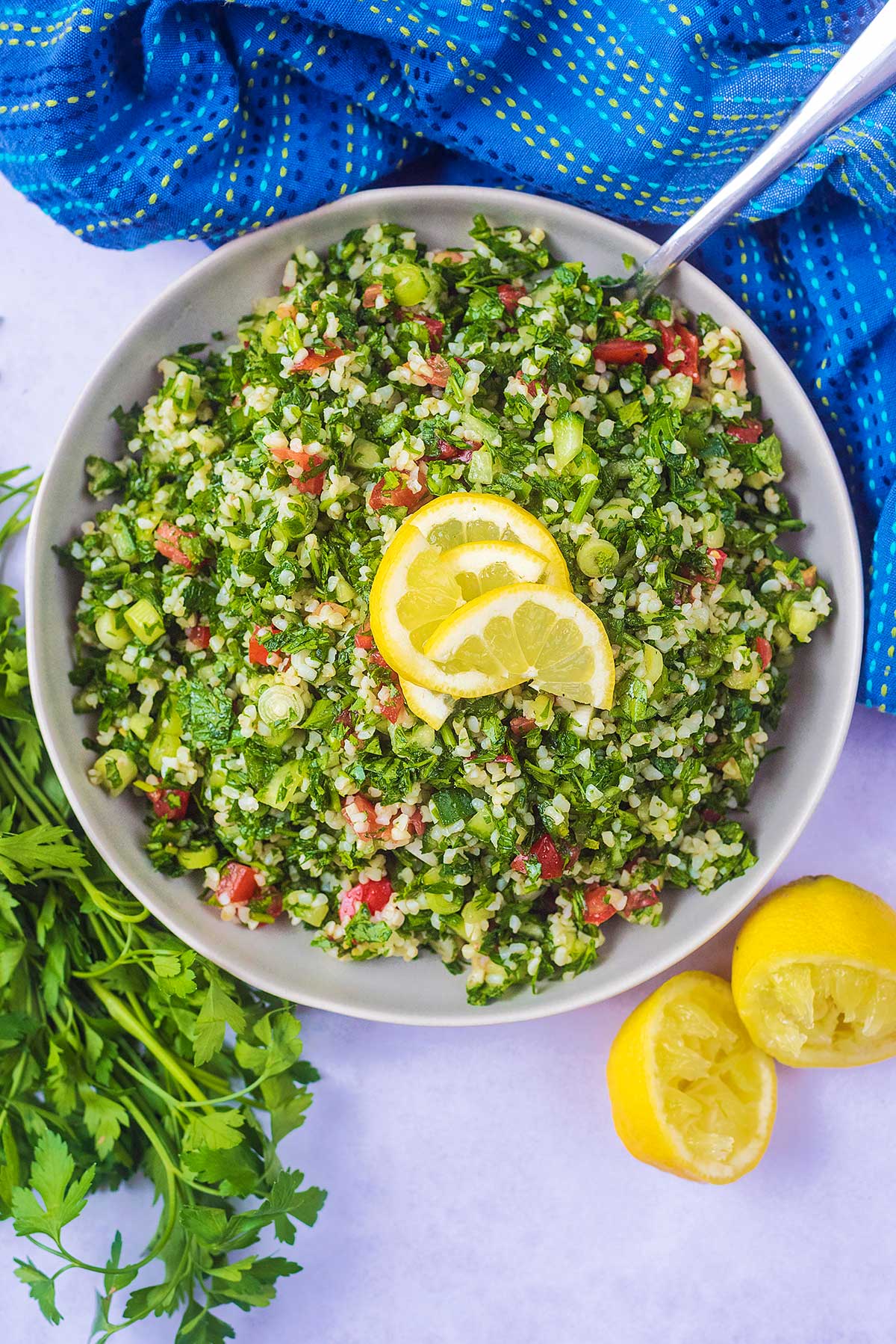 A bowl of tabbouleh with lemon slices on top.