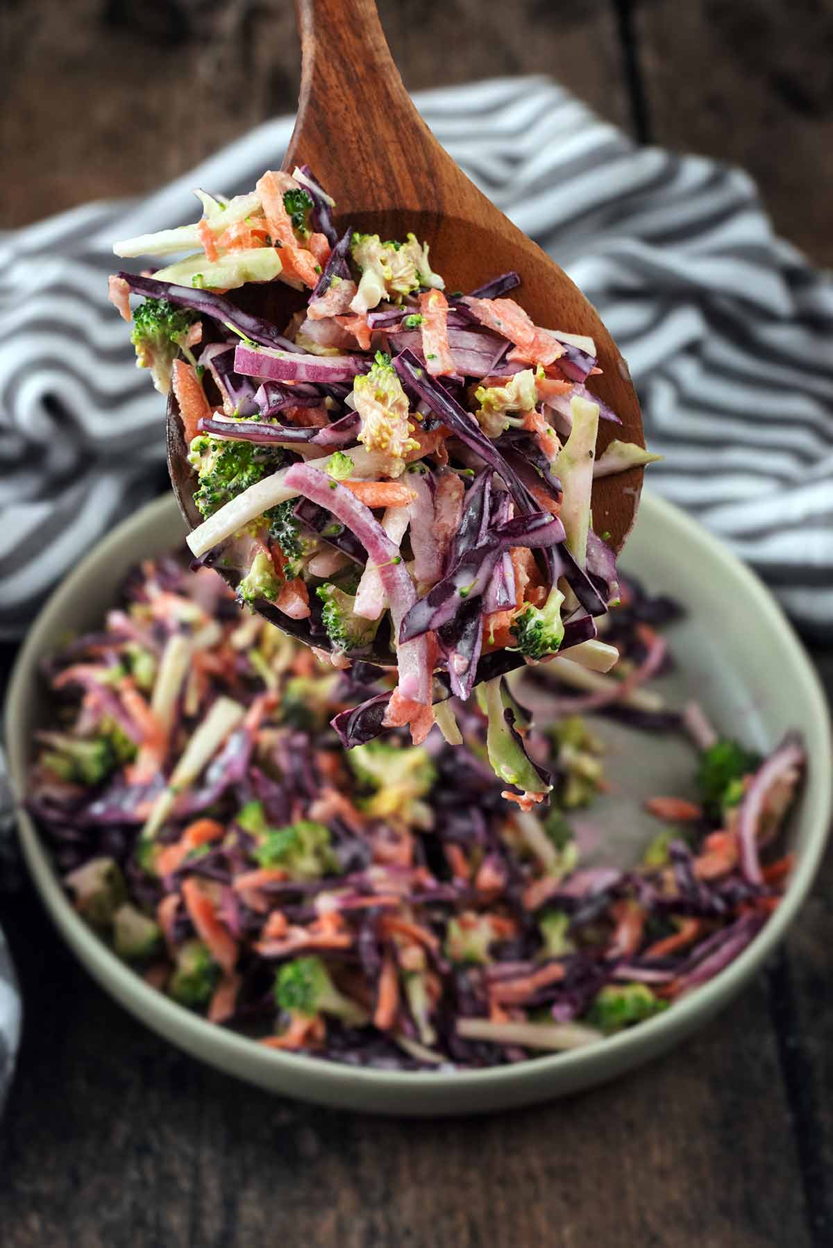 A wooden spoon lifting some slaw from a bowl.
