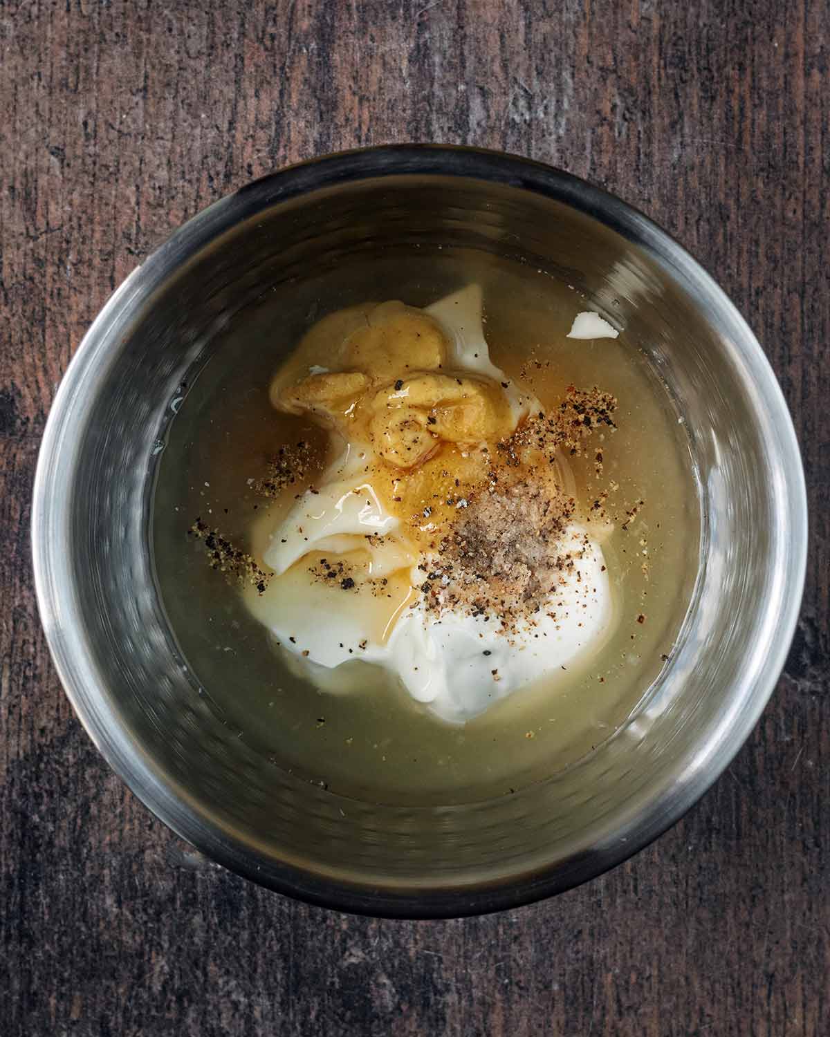 A mixing bowl containing yogurt, mayonnaise, lemon juice, mustard, salt and pepper.