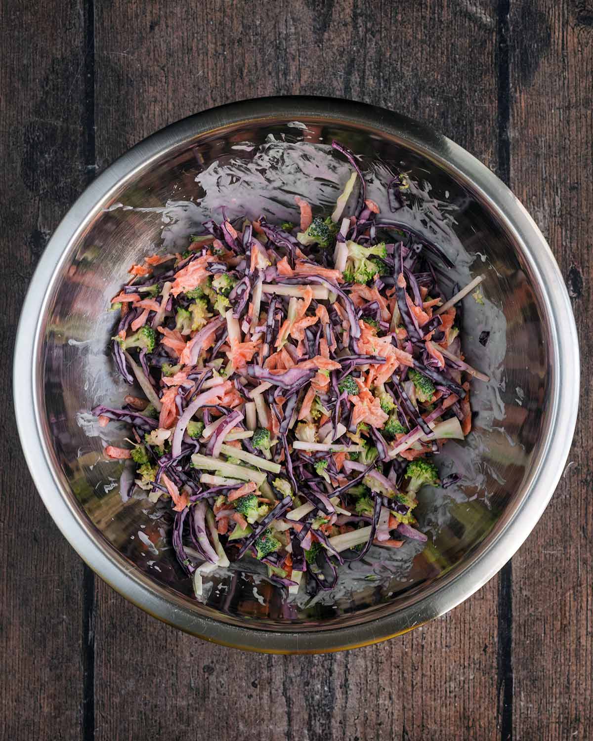 A bowl of slaw mixed together with dressing.
