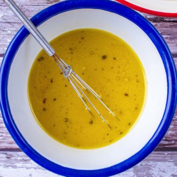 A bowl of Honey and Mustard Salad Dressing with a small whisk