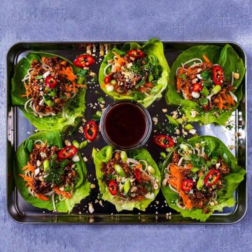 Six Asian Lettuce Wraps on a serving tray with a pot of hoisin sauce