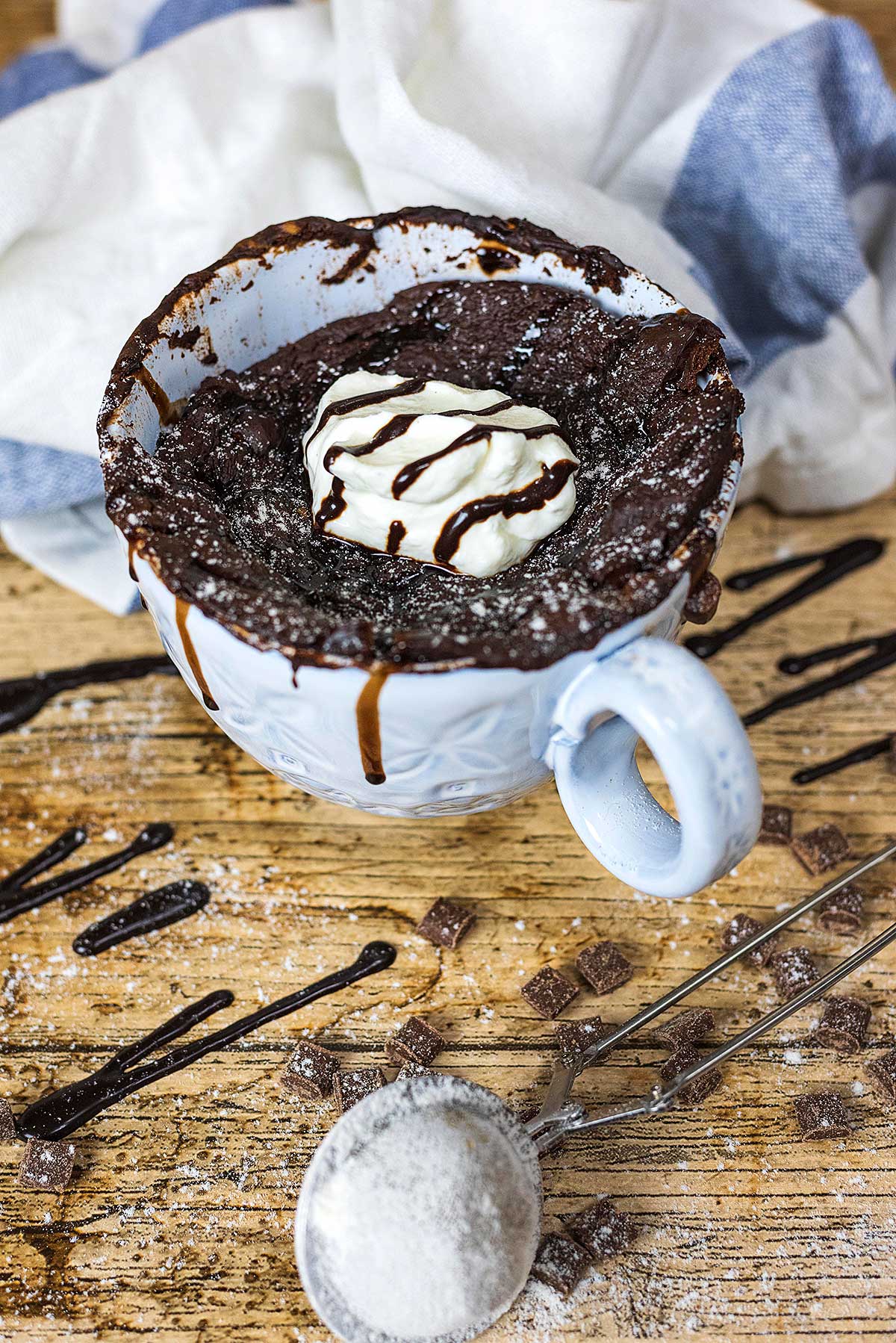 A large mug full of chocolate cake. topped with a dollop of yogurt.