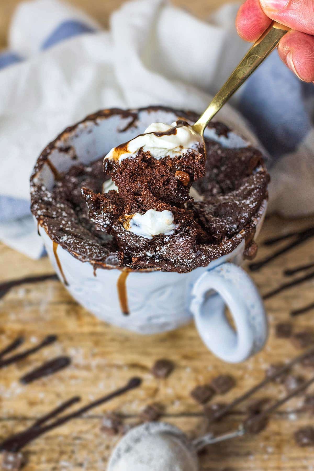 someone spooning out some chocolate cake from a large mug.