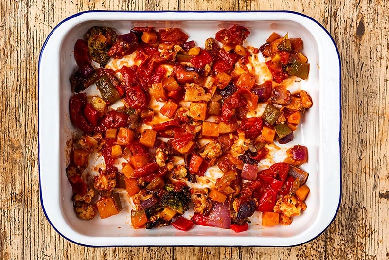 A baking dish with roasted vegetables in a tomato sauce spread across the bottom.
